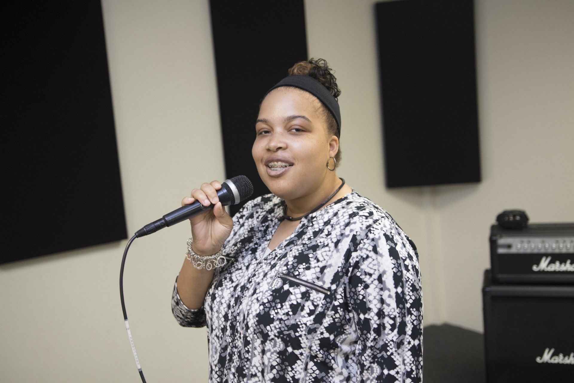 A vocalist records at the microphone in the Jazz Hands studio